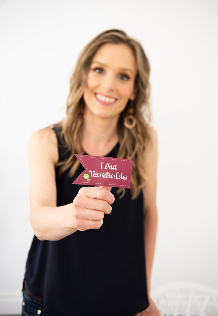 mother holding out an I am teachable sticker award badge to give to her child