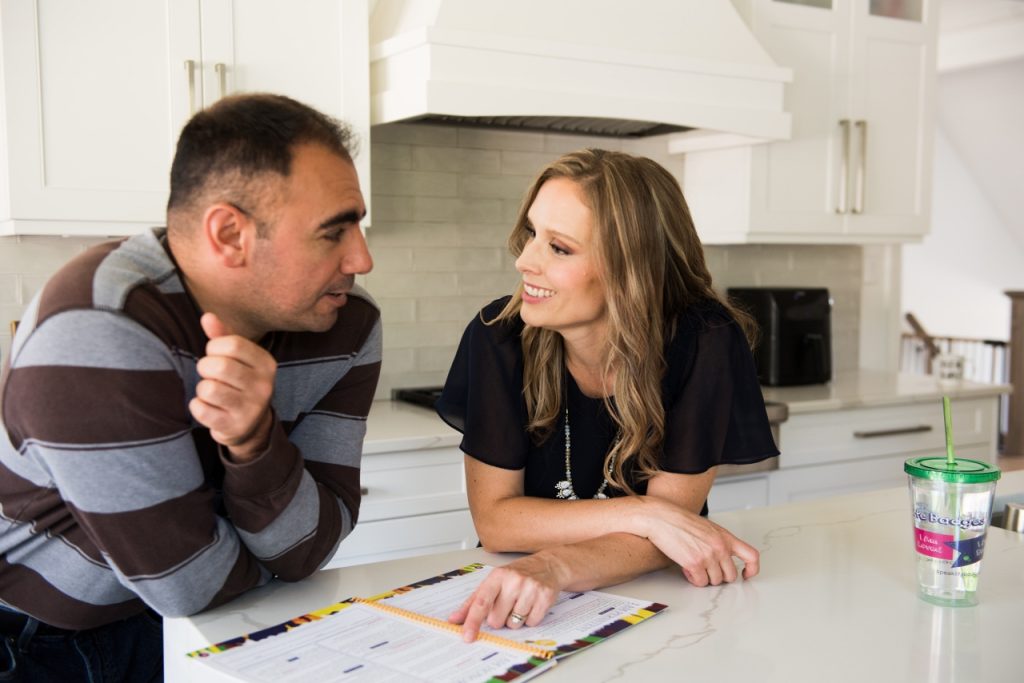 a couple, husband and wife, talking together at the kitchen counter